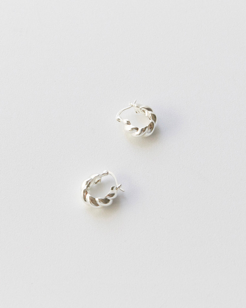 Two silver earrings on a light gray background