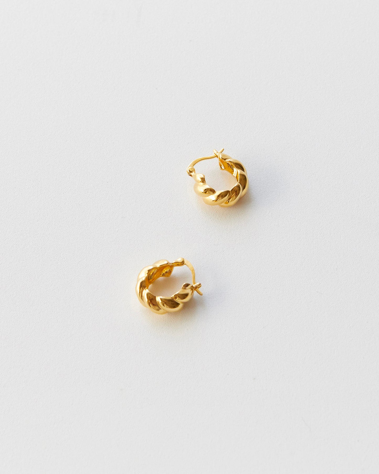 Gold hoop earrings on a light gray background