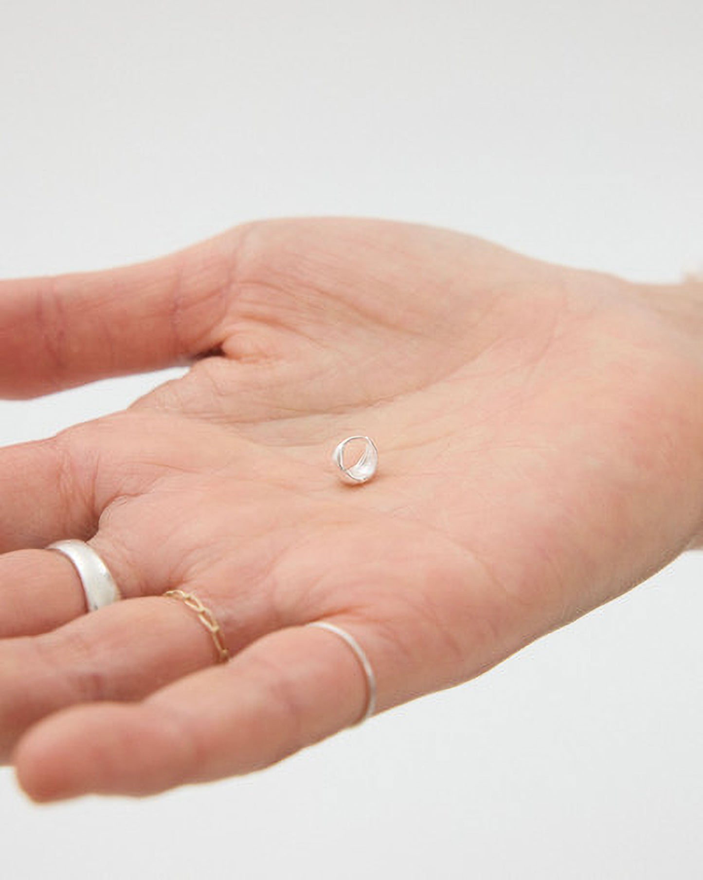Hand wearing multiple rings with a clear background