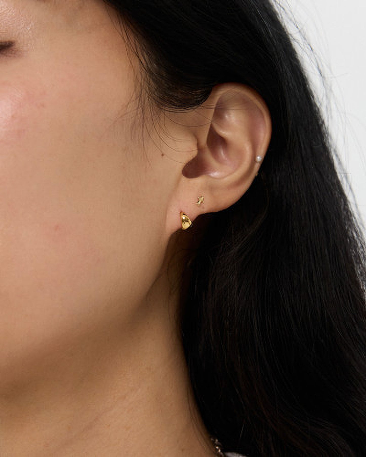 Close-up of a person wearing a gold earring.