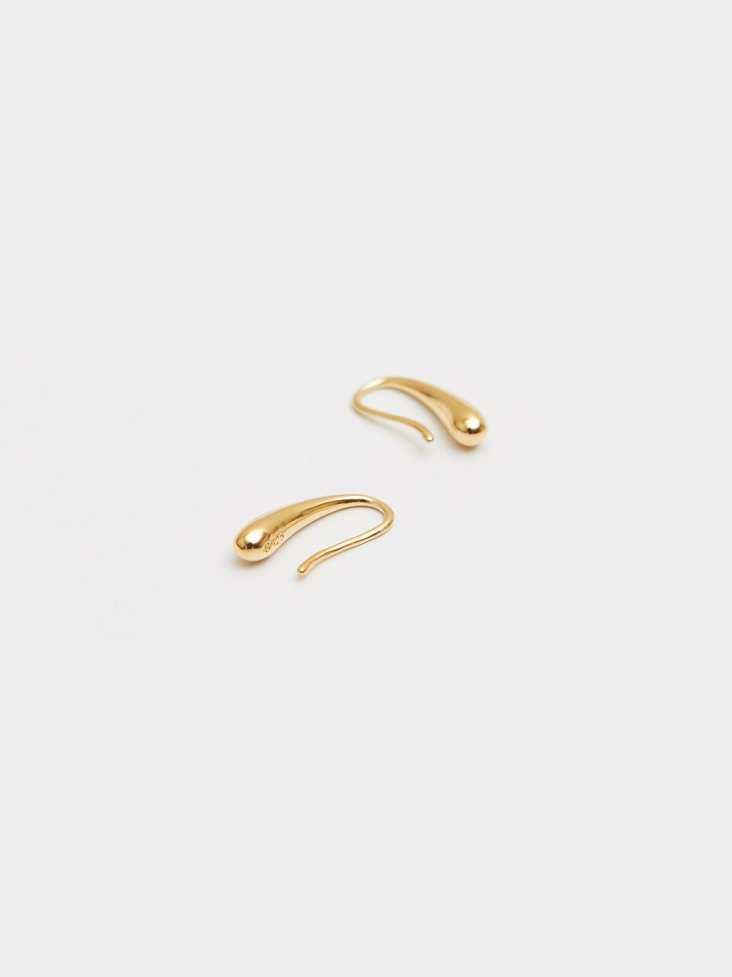 Two gold ear cuffs on a light beige background