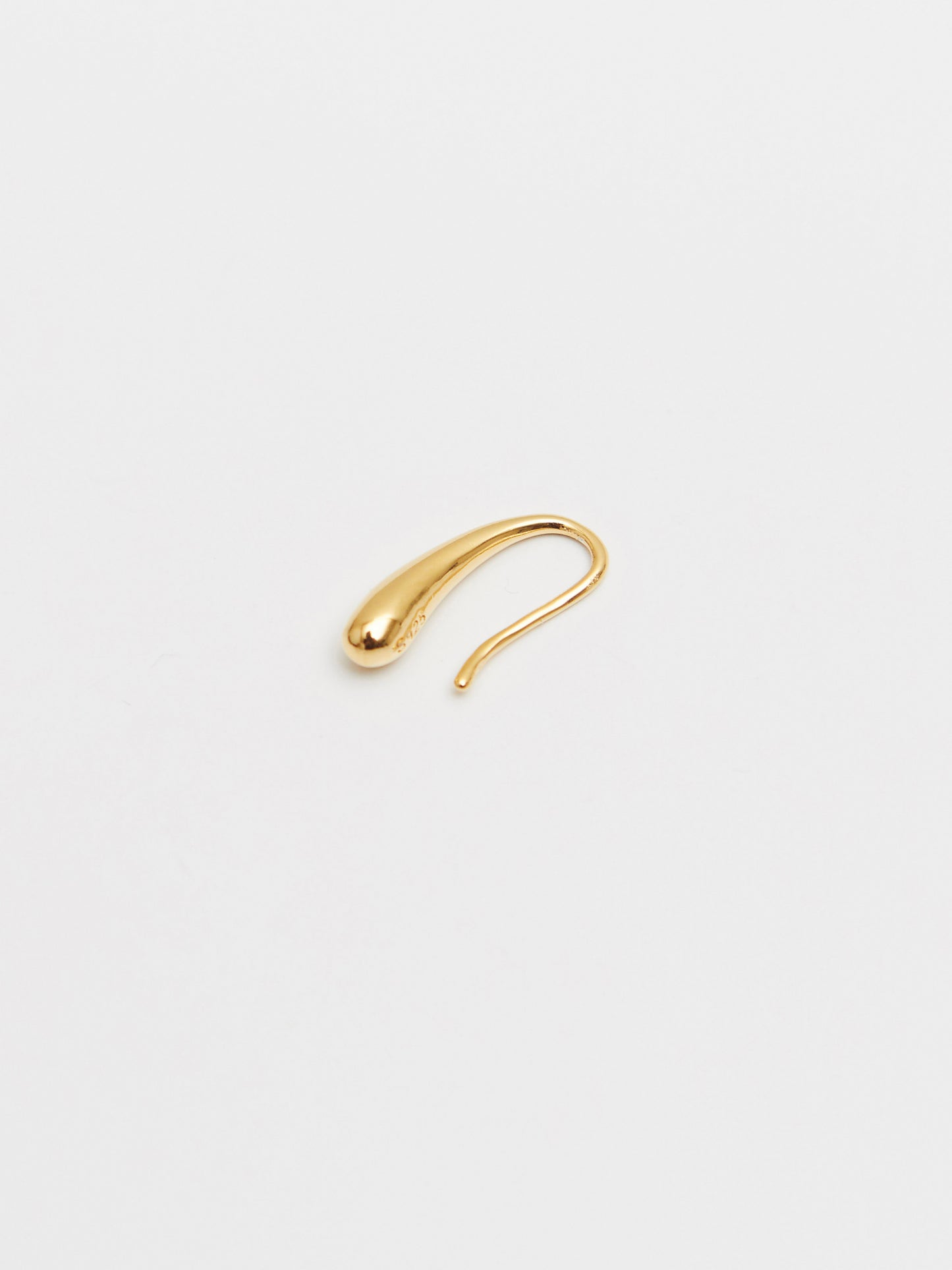 Gold earring on a light gray background