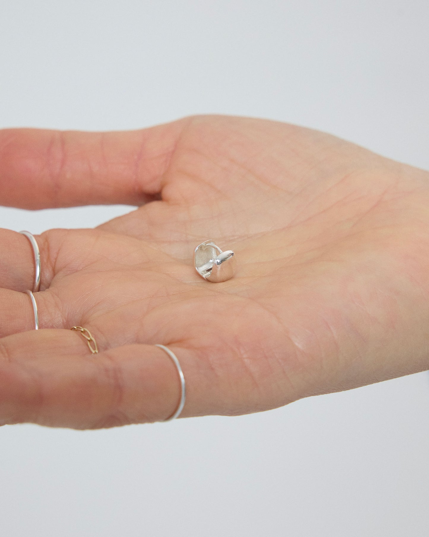 Silver earrings on a hand with a plain background