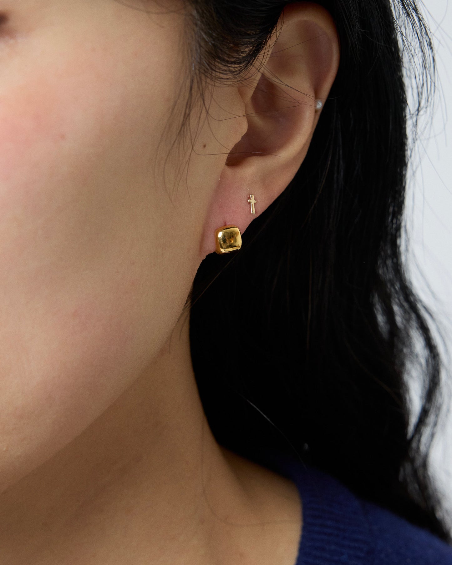gold square stud earrings worn on ear, polished cube shape, minimal modern gold jewelry styling