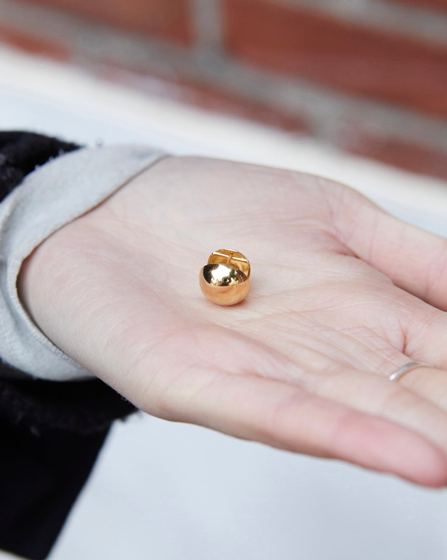 gold dome stud earring on hand size reference reflective minimal jewelry