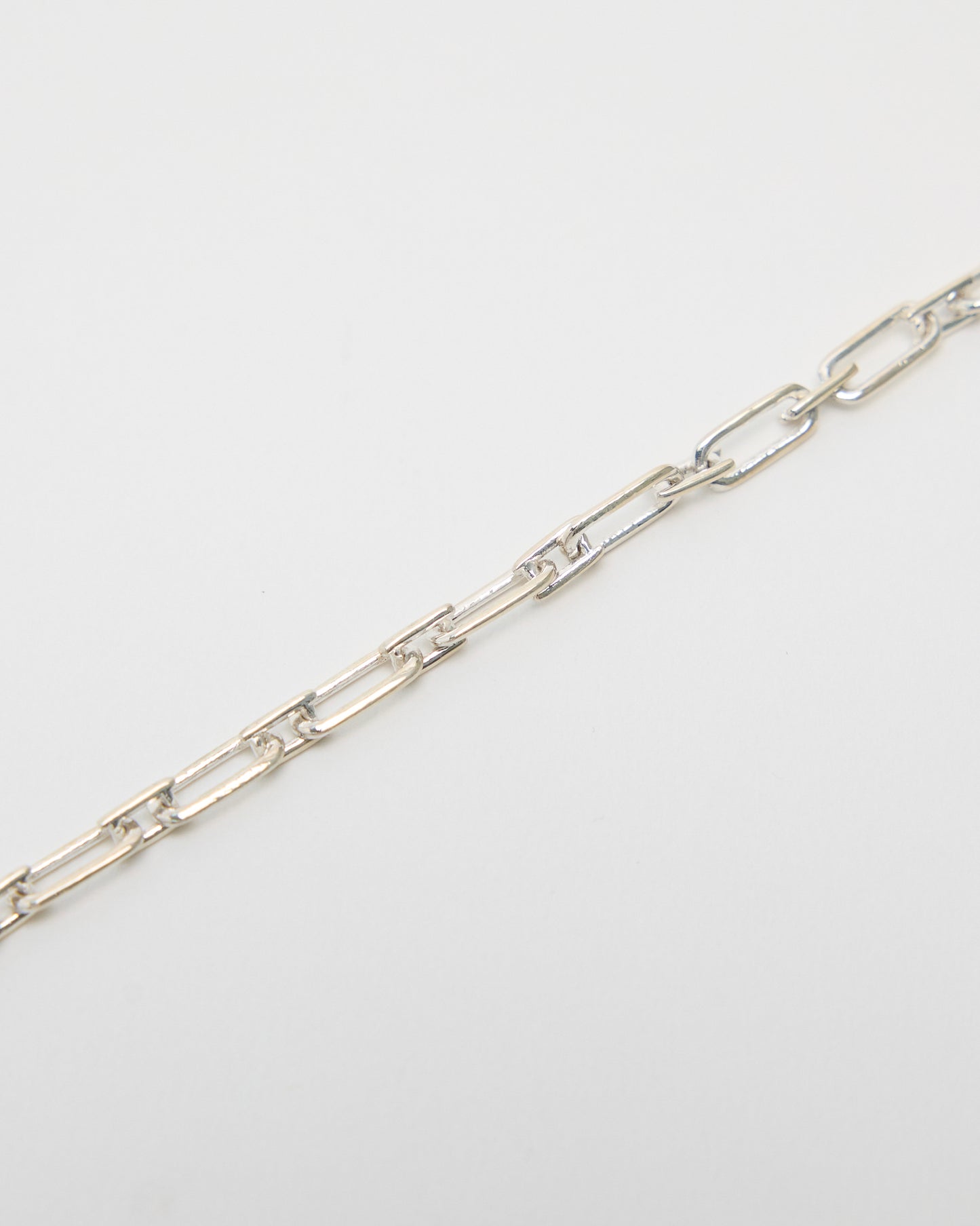 sterling silver chain detail, interlocking rectangular links close-up, polished metal texture, geometric jewelry construction, high-quality link chain craftsmanship