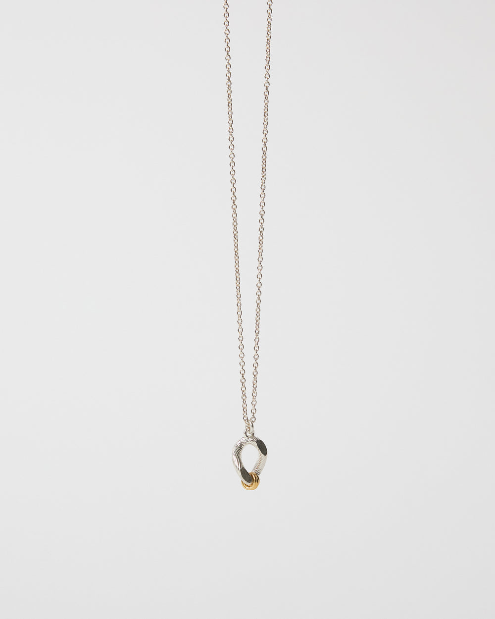 Detailed angled view of an organic mixed metal pendant necklace on chain