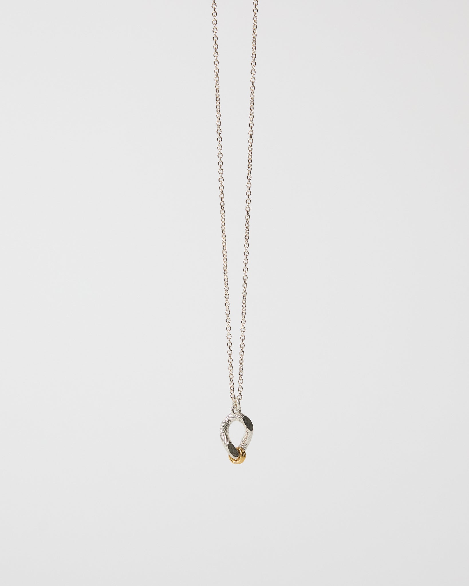 Detailed angled view of an organic mixed metal pendant necklace on chain
