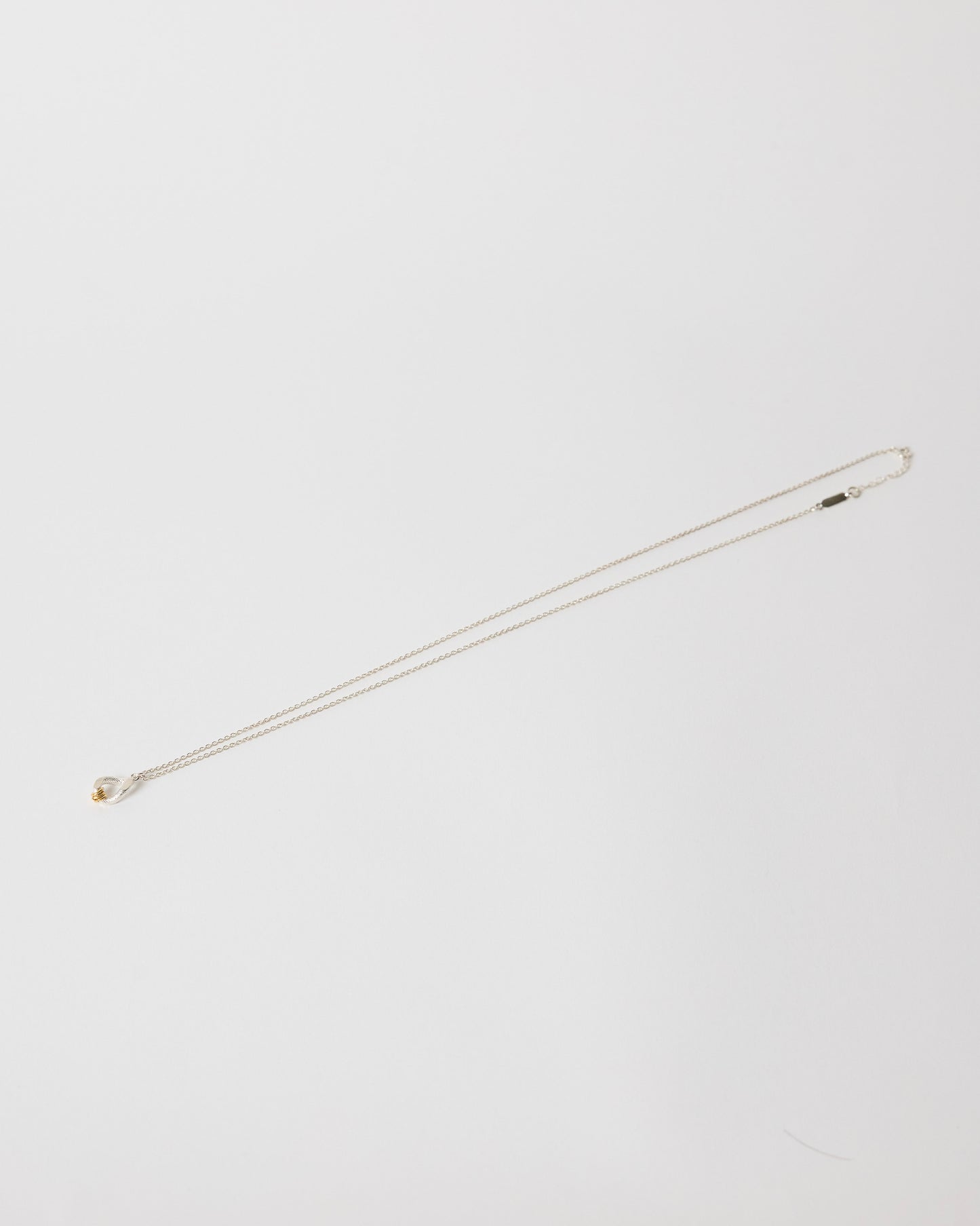 Silver necklace on a light gray background