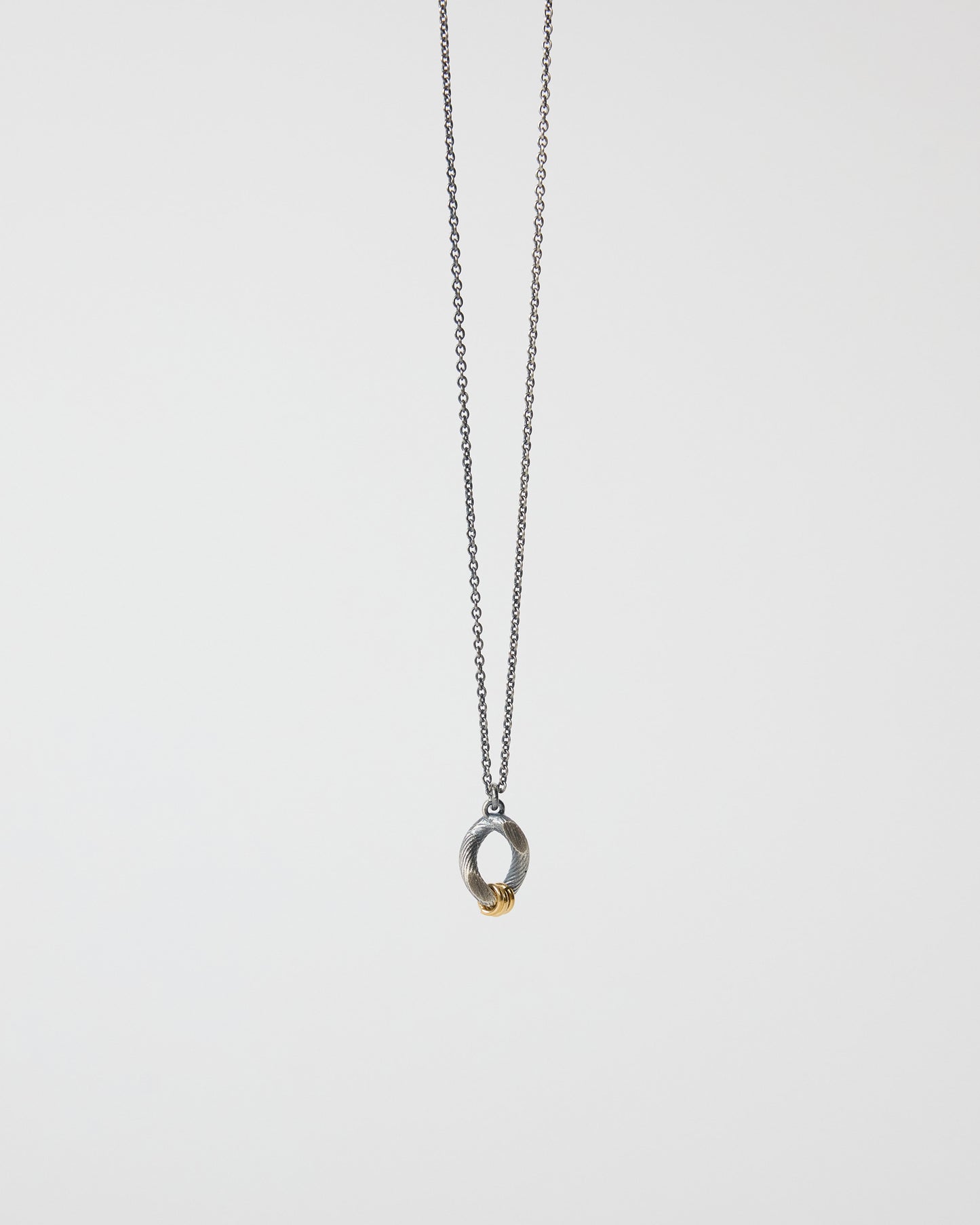 Mixed metal pendant necklace featuring oxidized antique silver finish and gold accent rings
