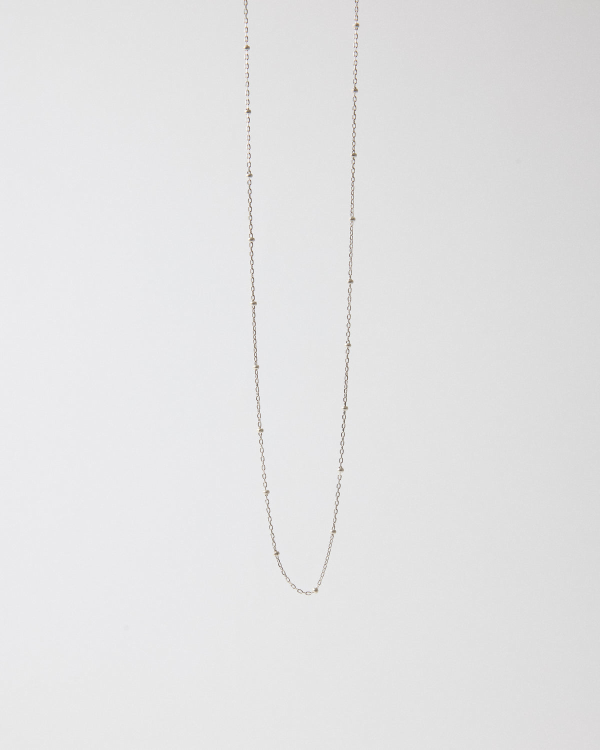Sterling silver ball station chain necklace hanging on a light gray background – HANNA543 N1057 starlit dot chain