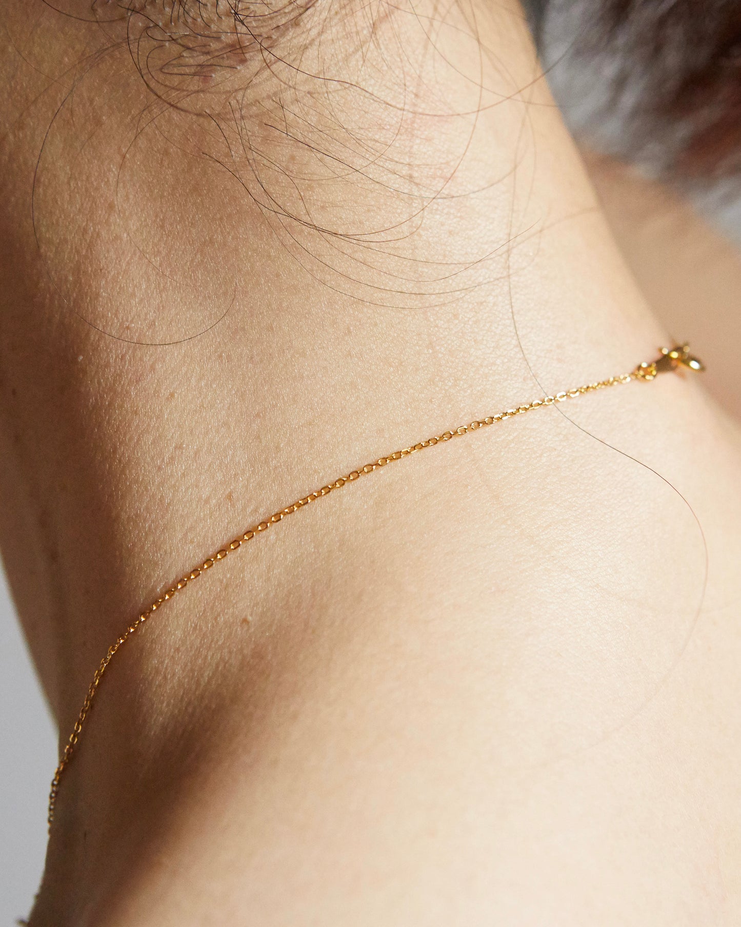 Back neck view showing thin gold chain necklace clasp detail