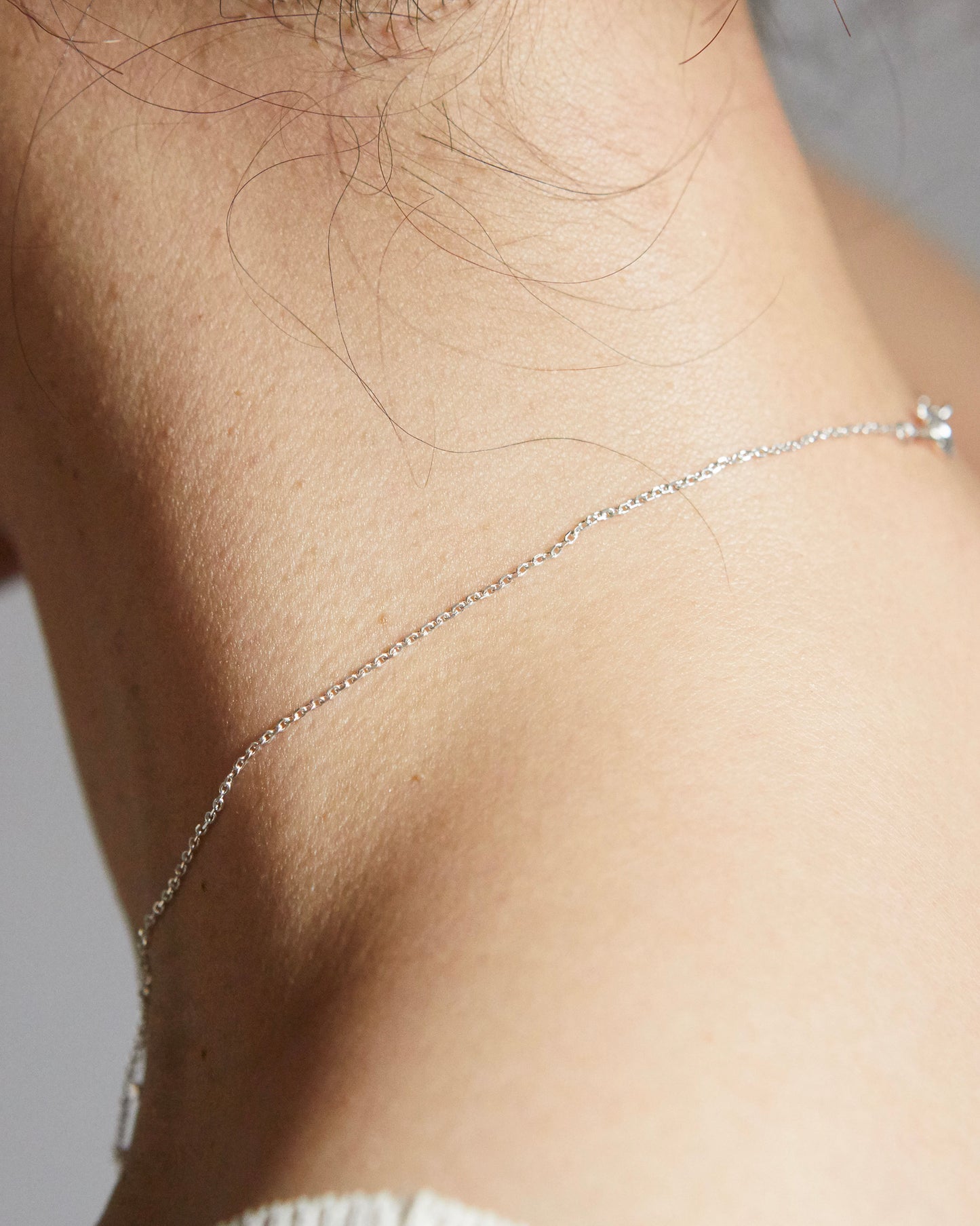 Back neck view showing thin silver chain necklace clasp detail