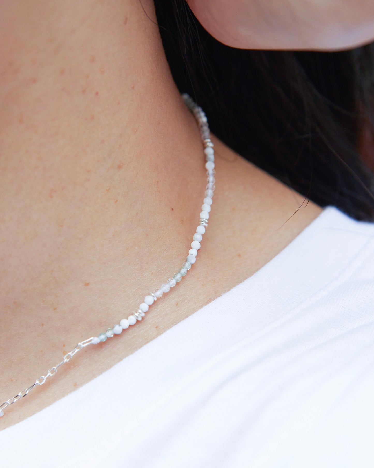 close-up view of necklace worn at the neck, showing fine beads against skin