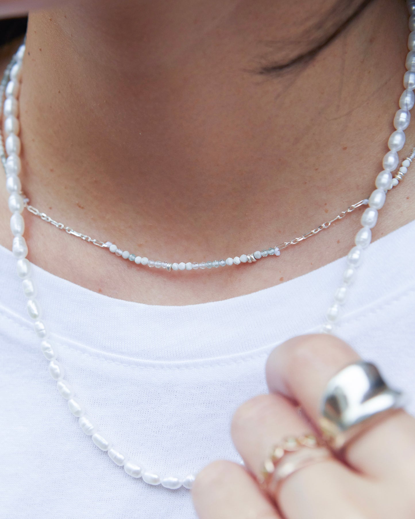 styling shot layering the necklace with pearls and other rings
