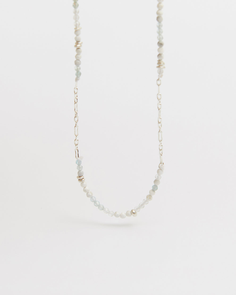 floating product shot of beaded and silver chain necklace centered against white
