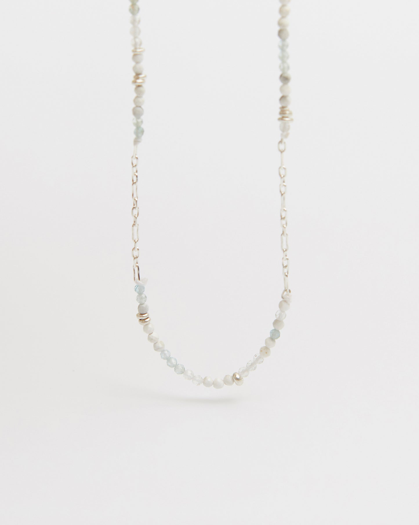 floating product shot of beaded and silver chain necklace centered against white