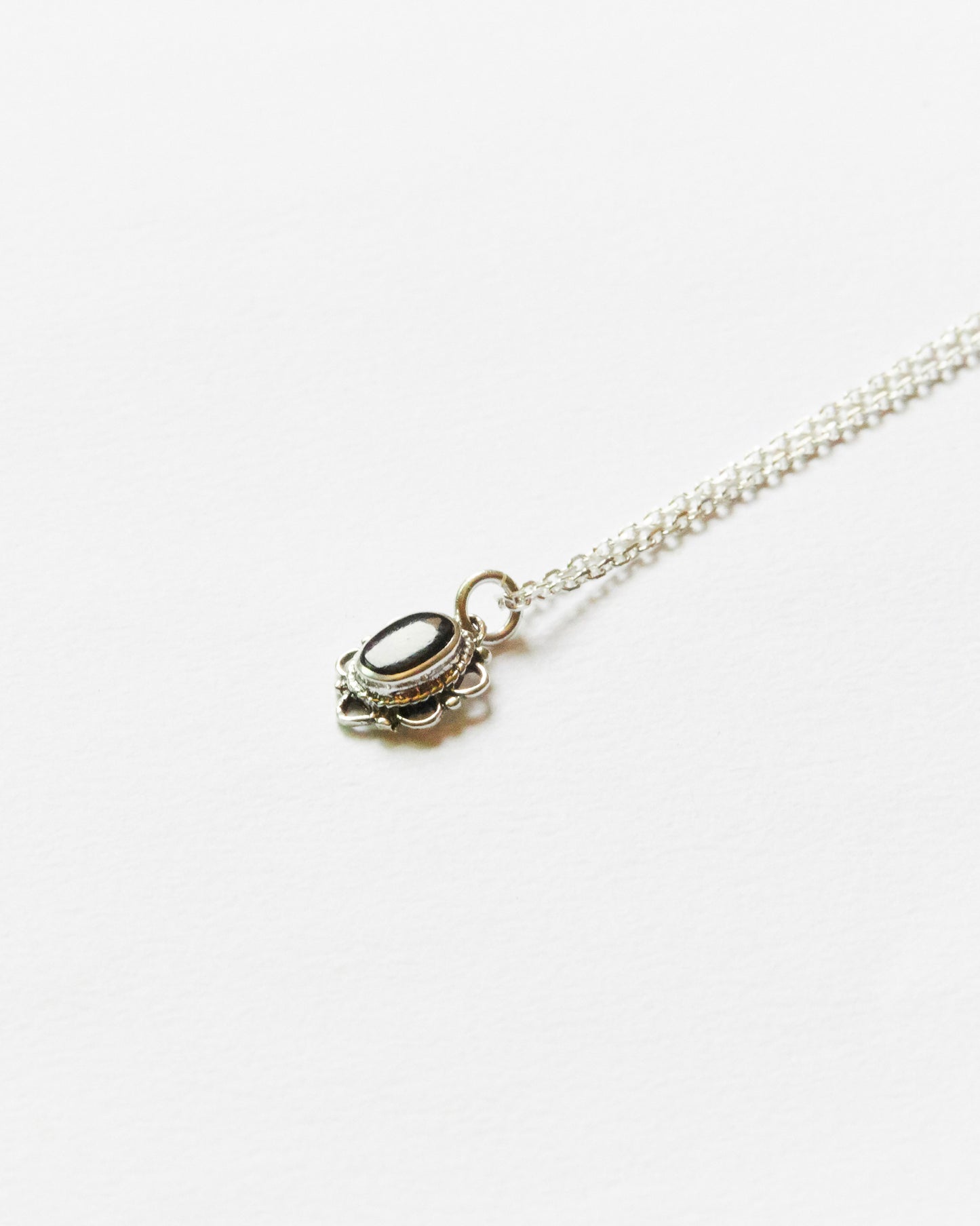 Necklace with soft white oval stone pendant floating midair against clean backdrop