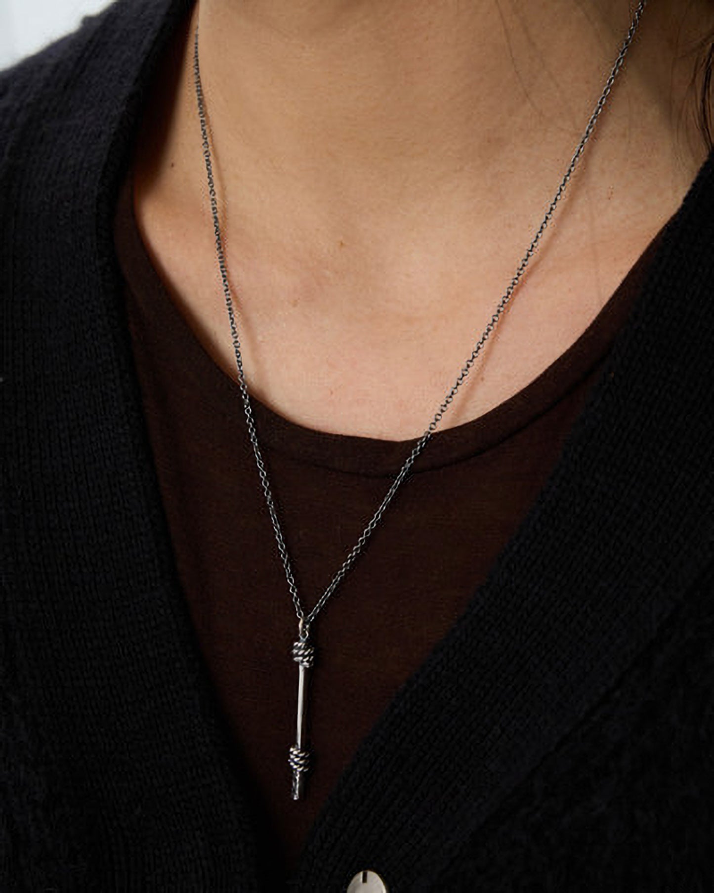 Necklace with a unique pendant worn by a person against a dark background