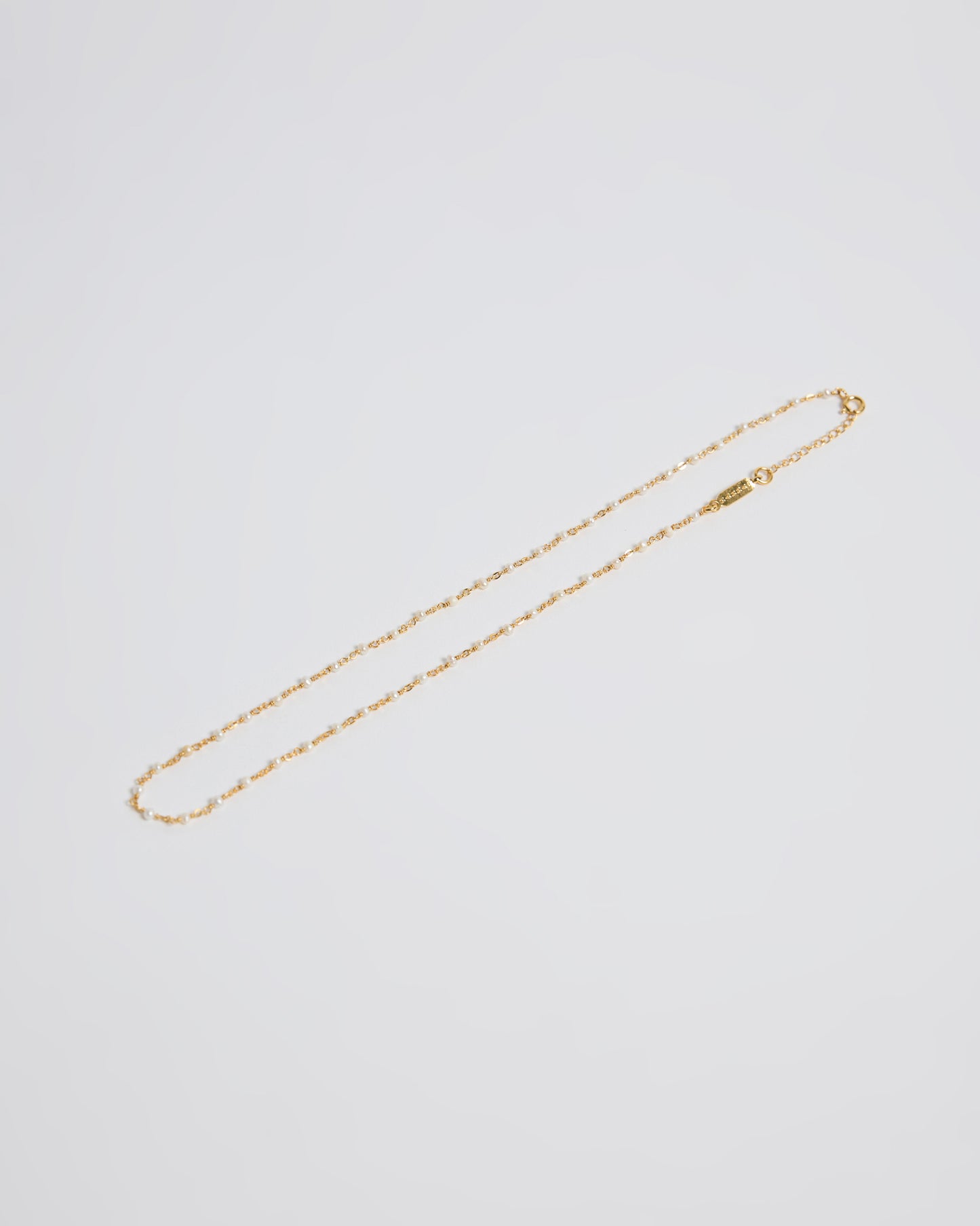 laid flat showing the fine gold chain with tiny pearl accents