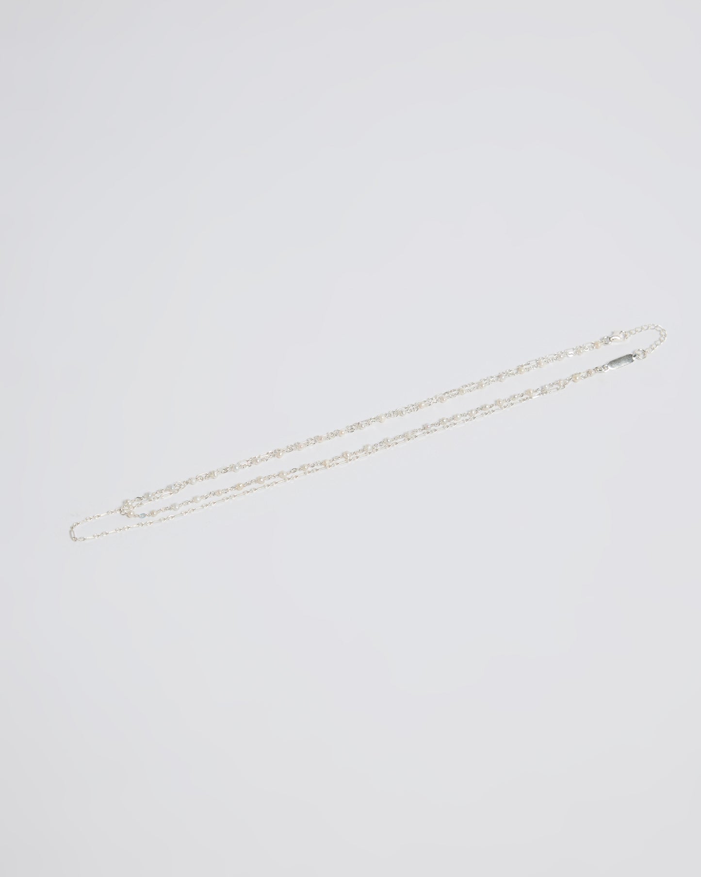 silver necklaces laid flat showing a pearl chain and a simple chain combination