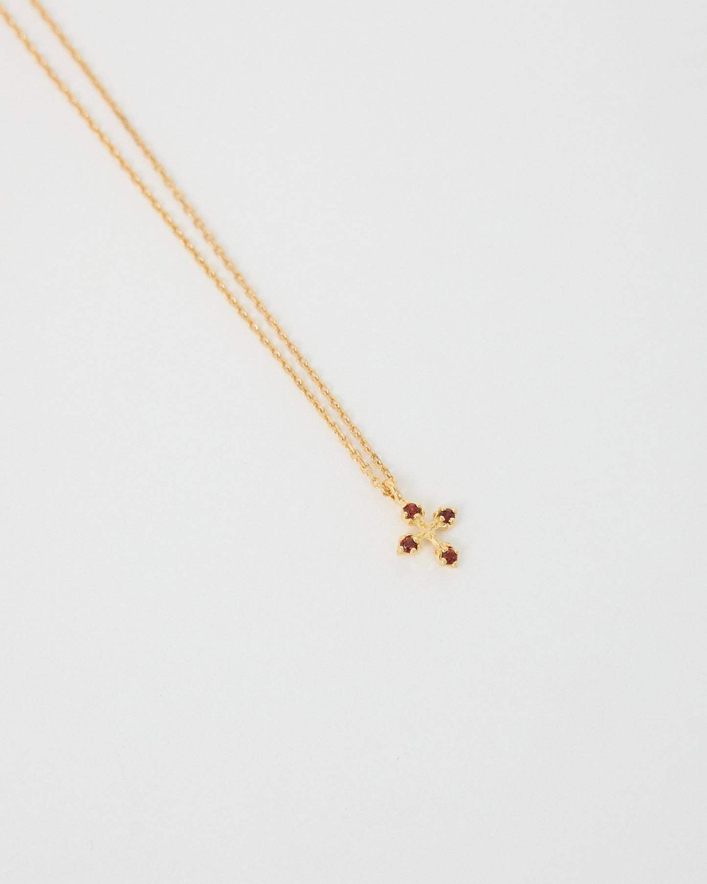Gold necklace with a small cross pendant on a light gray background