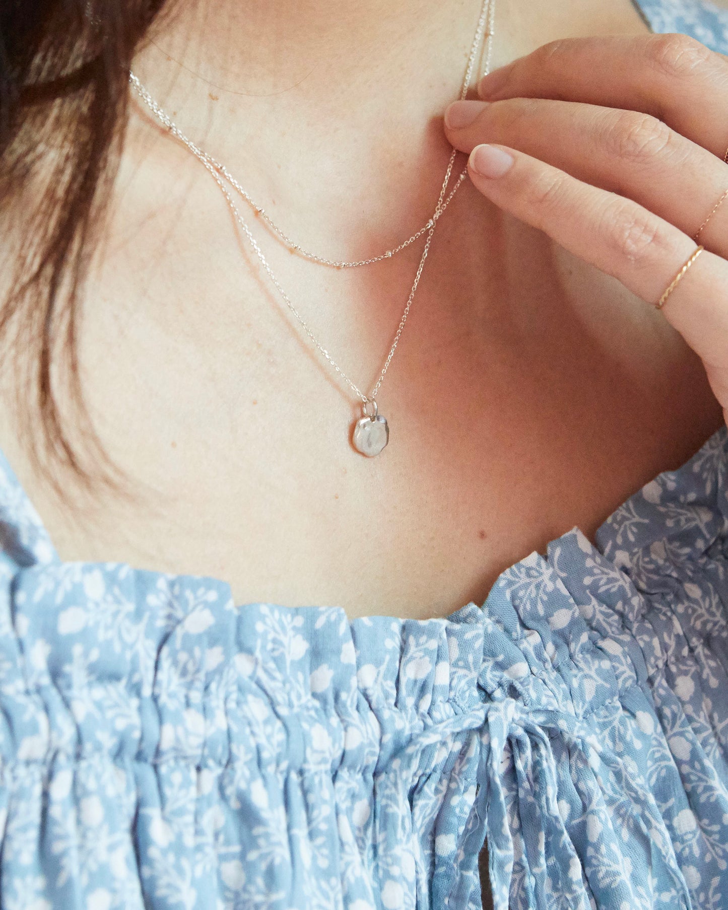 Model wearing N358 layered silver necklace with subtle round pendant and floral dress