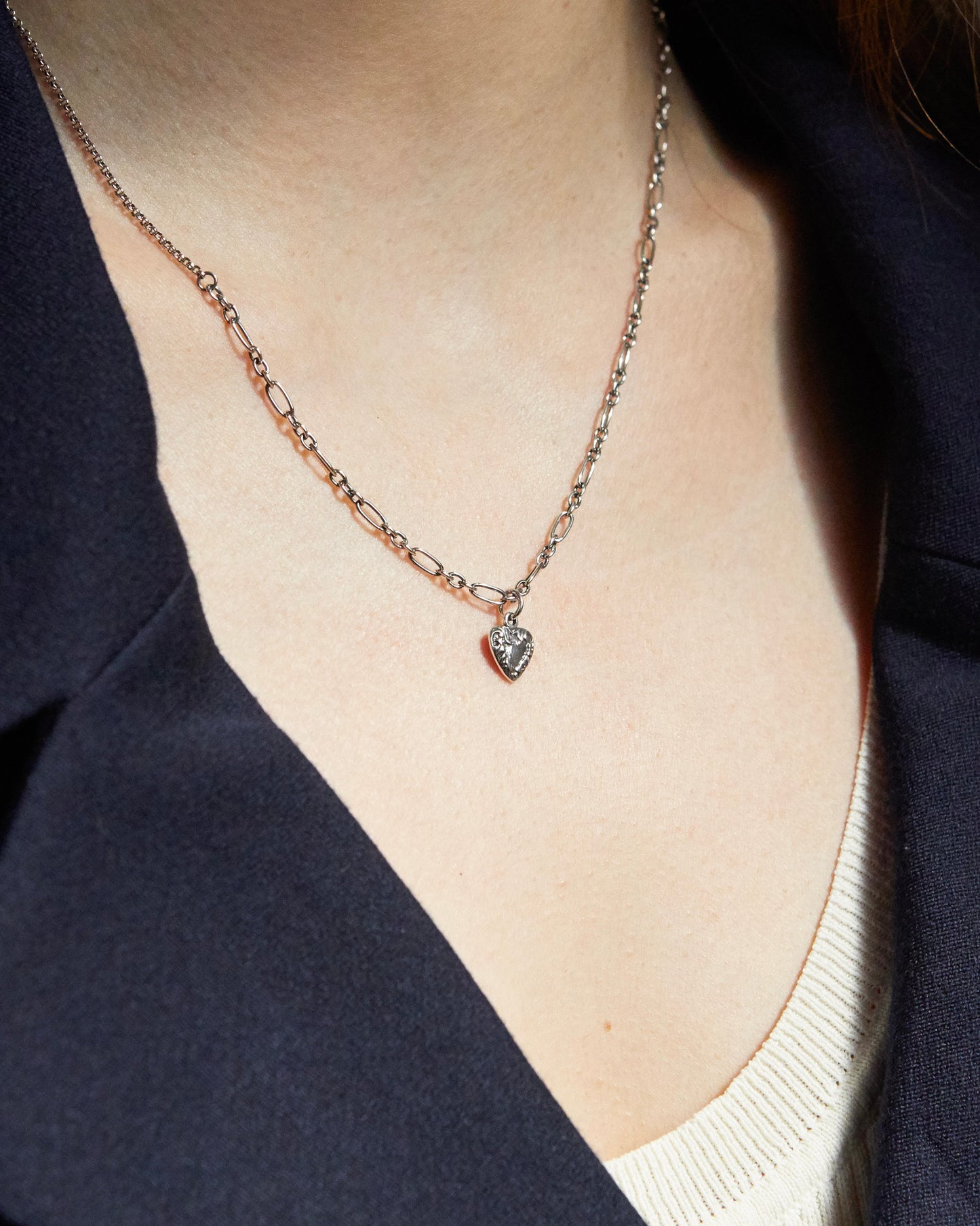 Macro shot of antique-style silver heart pendant and textured chain
