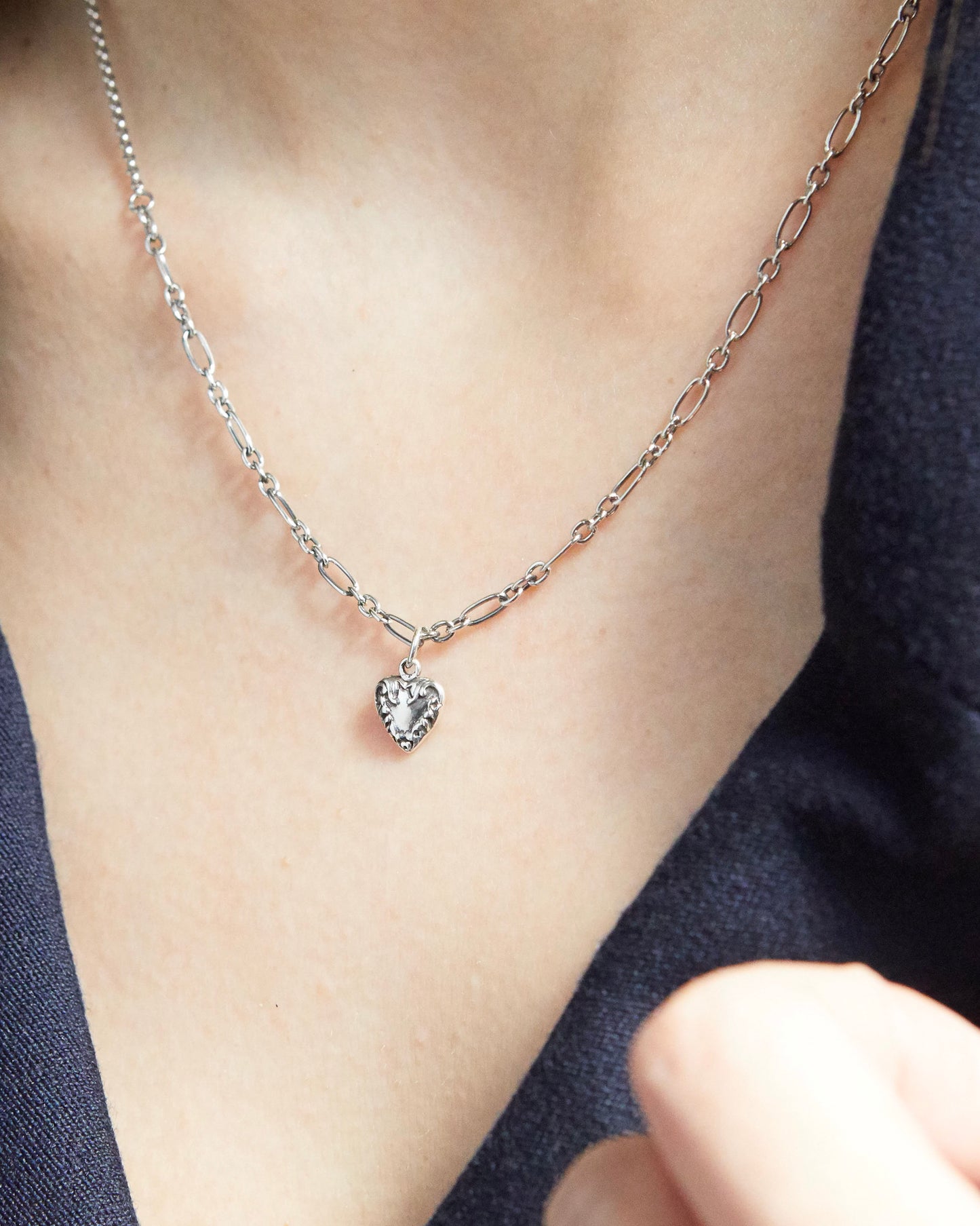 silver-toned heart pendant necklace styled with gold rings and navy outfit