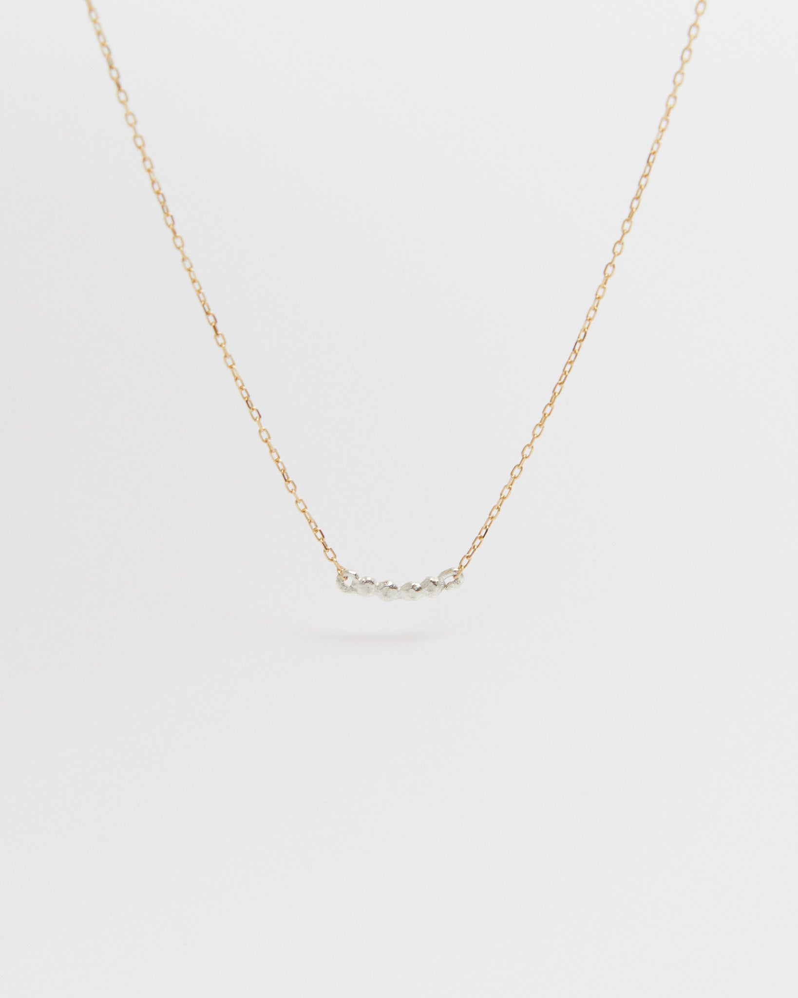 Gold necklace on a light gray background