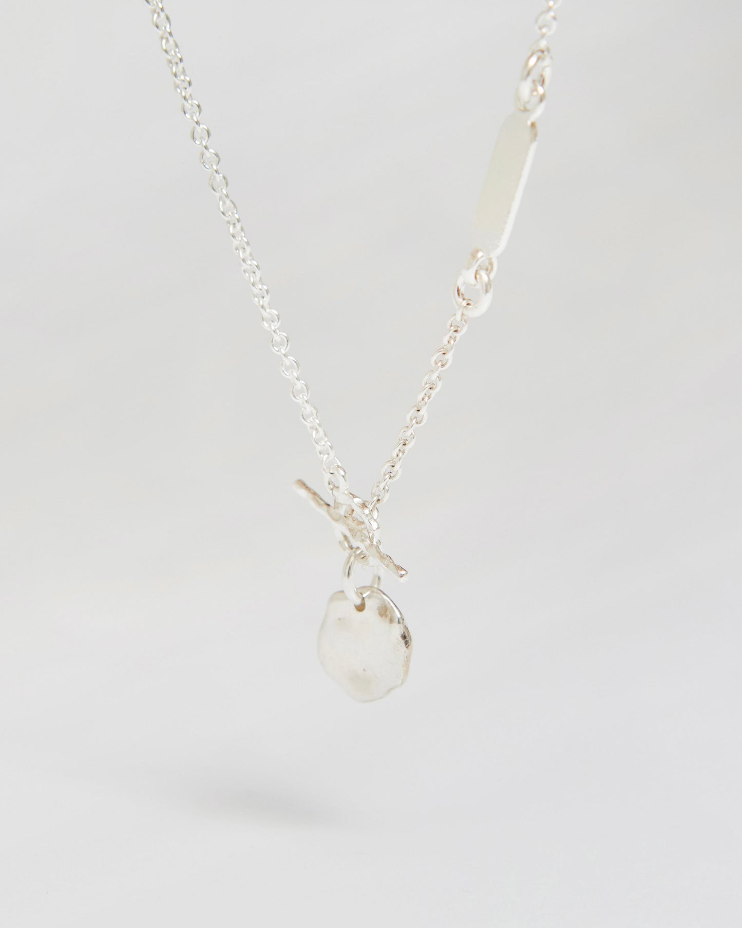 Silver necklace with organic irregular pendant hanging on chain