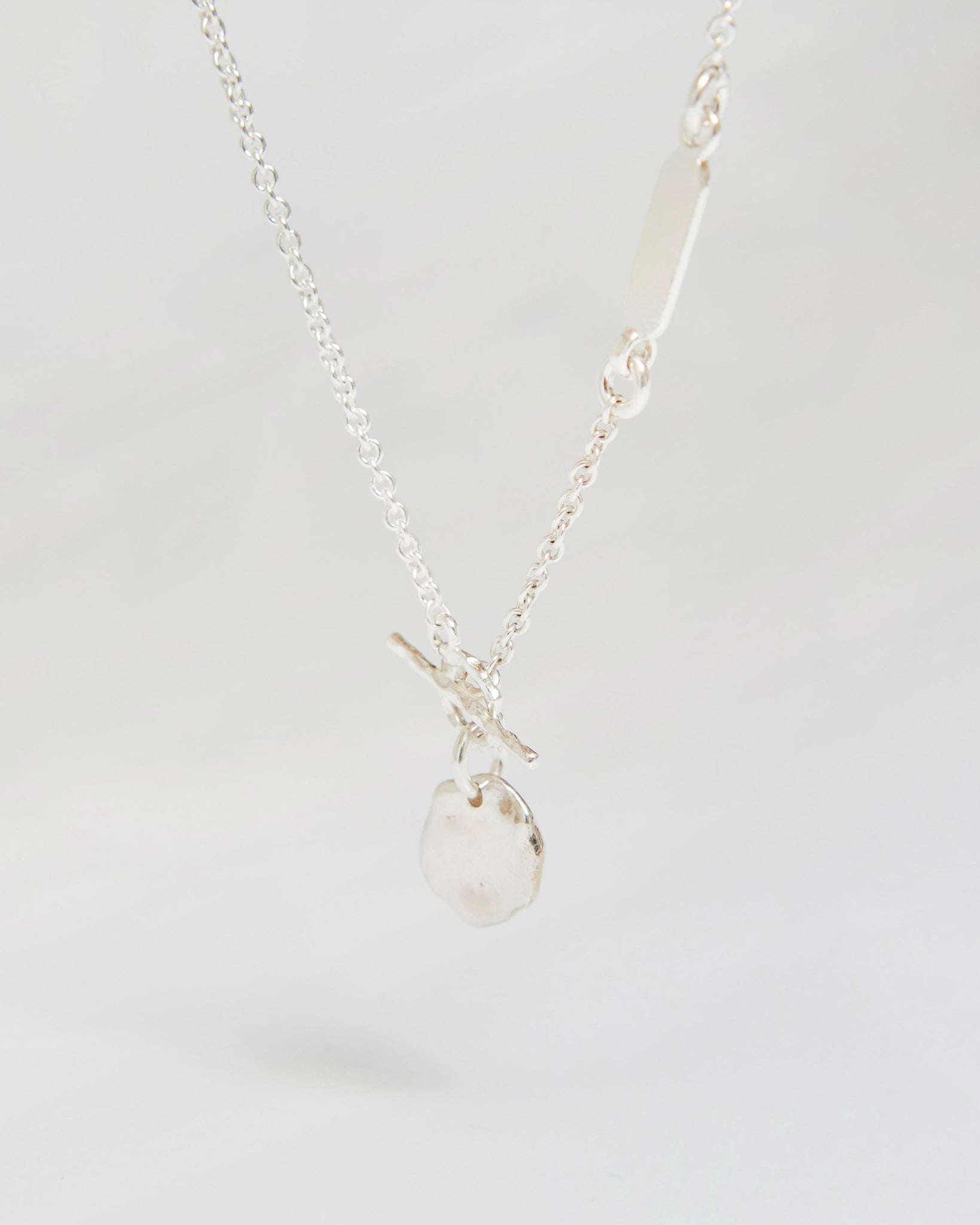 Silver necklace with organic irregular pendant hanging on chain