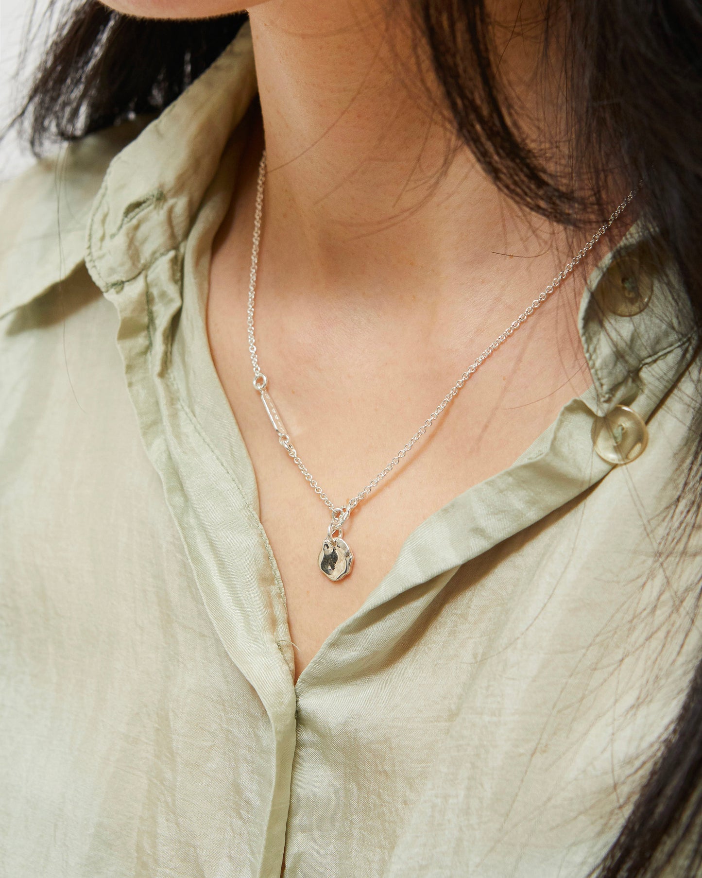 Silver necklace with abstract pendant worn on neck with soft styling