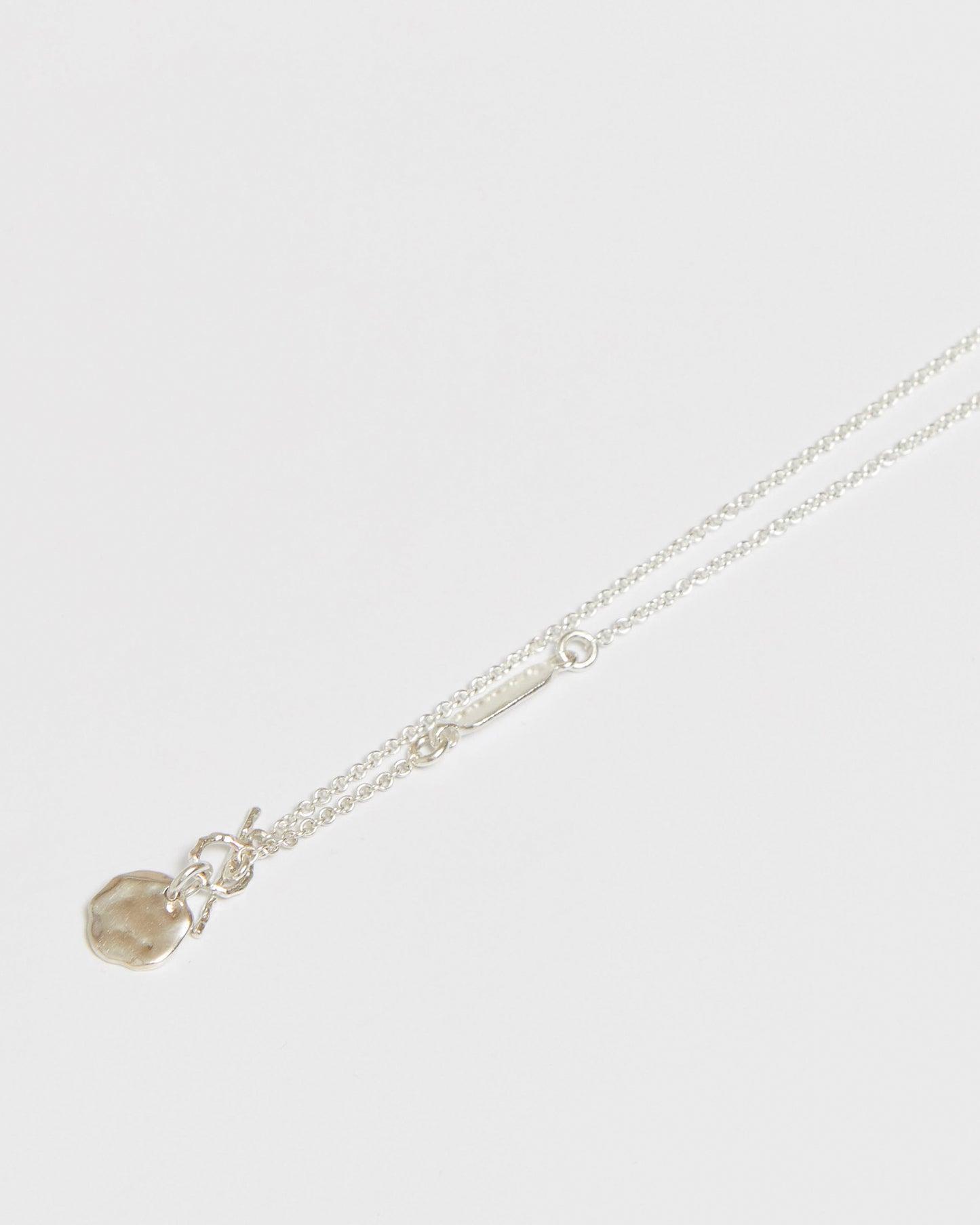 Silver necklace draped over hand showing pendant and chain detail