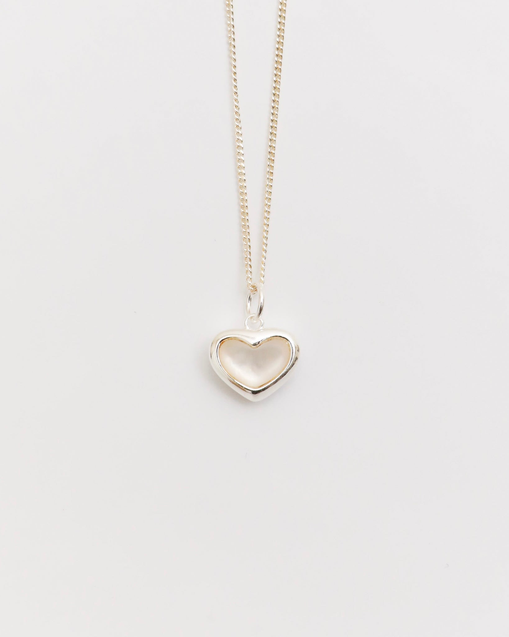 silver heart necklace with mother of pearl pendant on fine chain, minimal jewelry flat lay