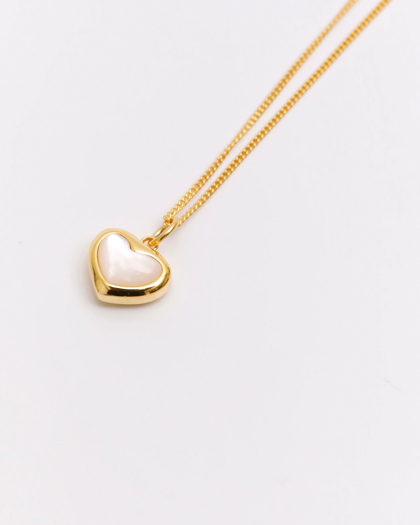 minimal gold heart necklace with mother of pearl detail on white background