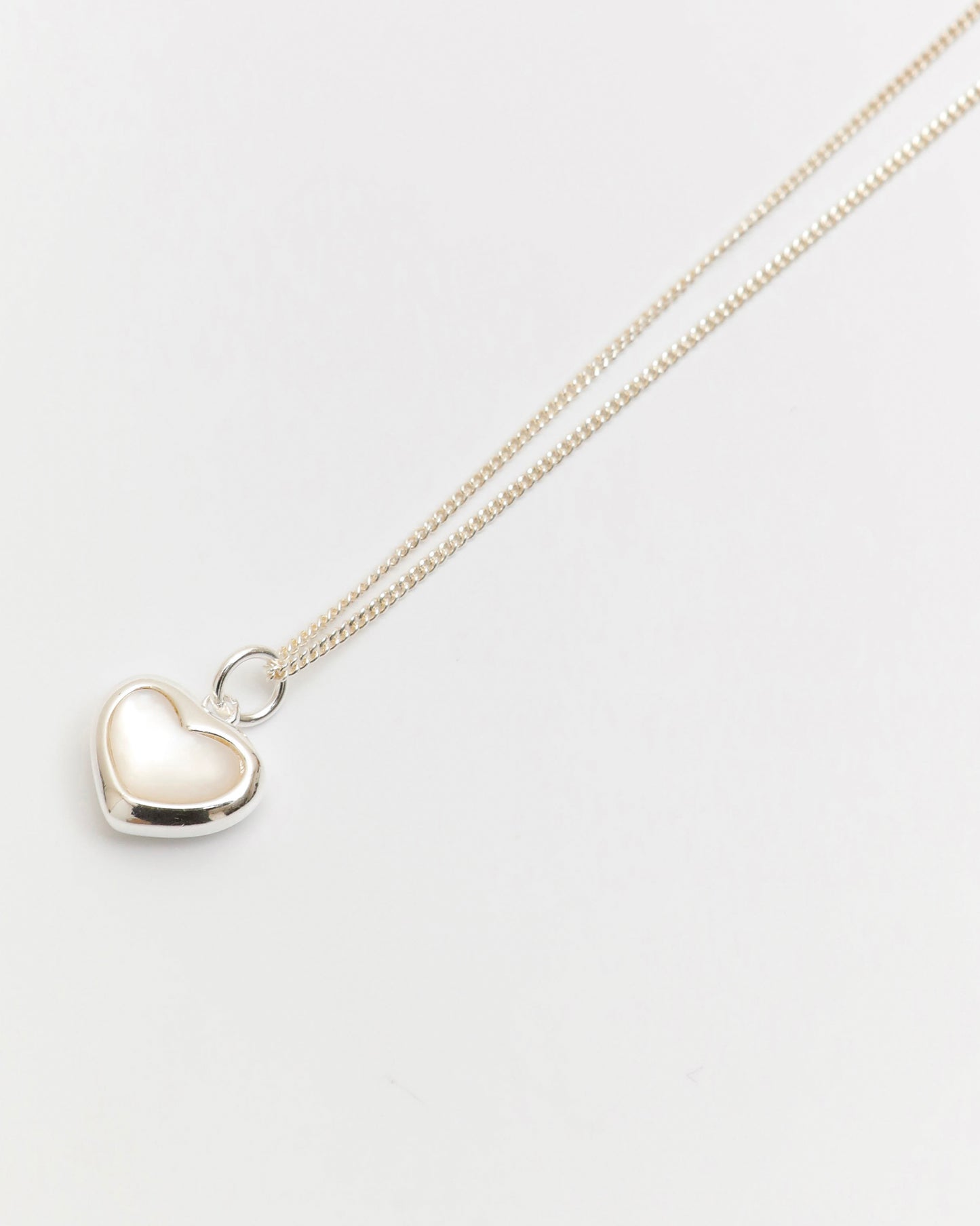 minimal silver heart necklace with mother of pearl detail on white background