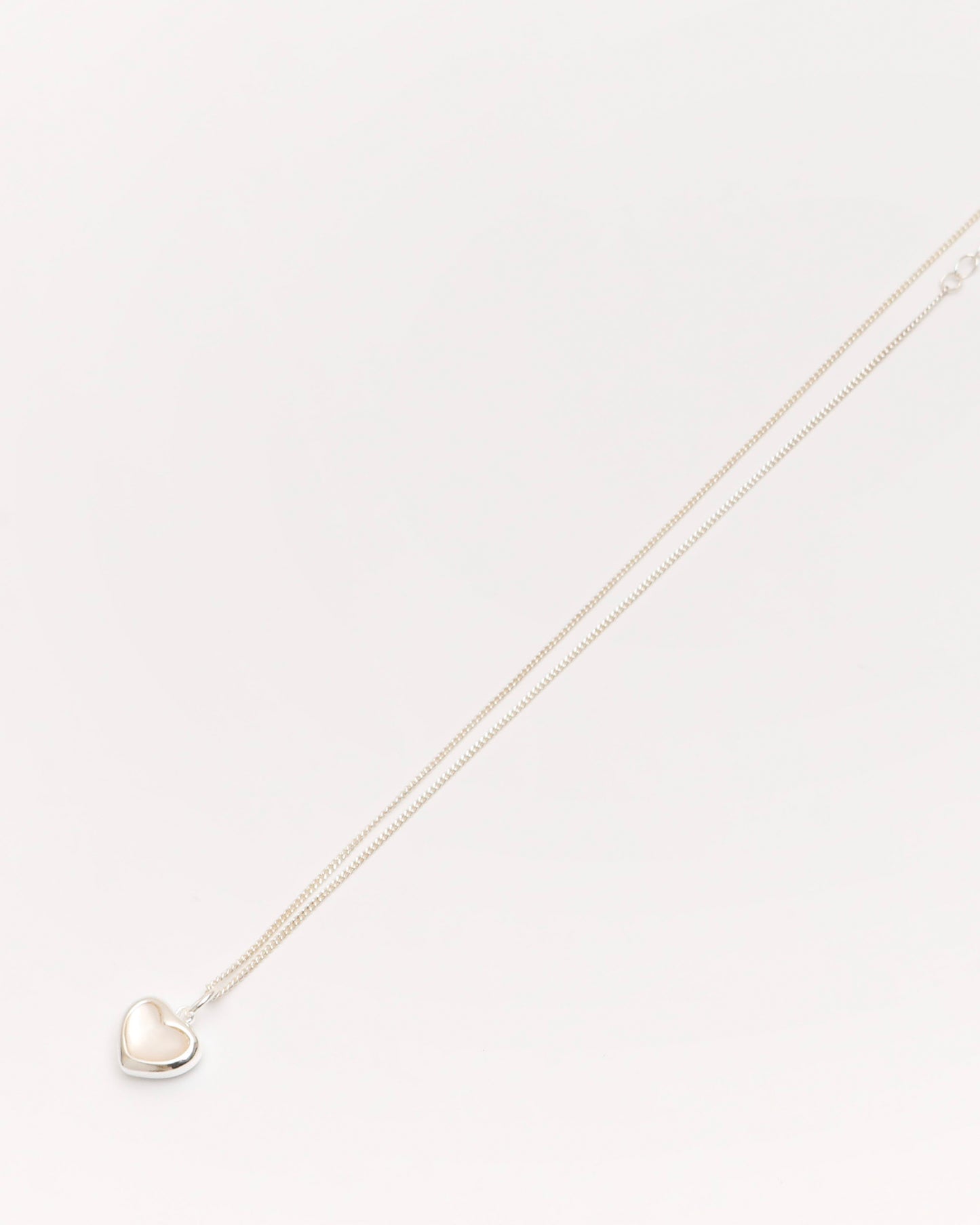 silver heart pendant necklace with soft pearl center, minimalist jewelry photography