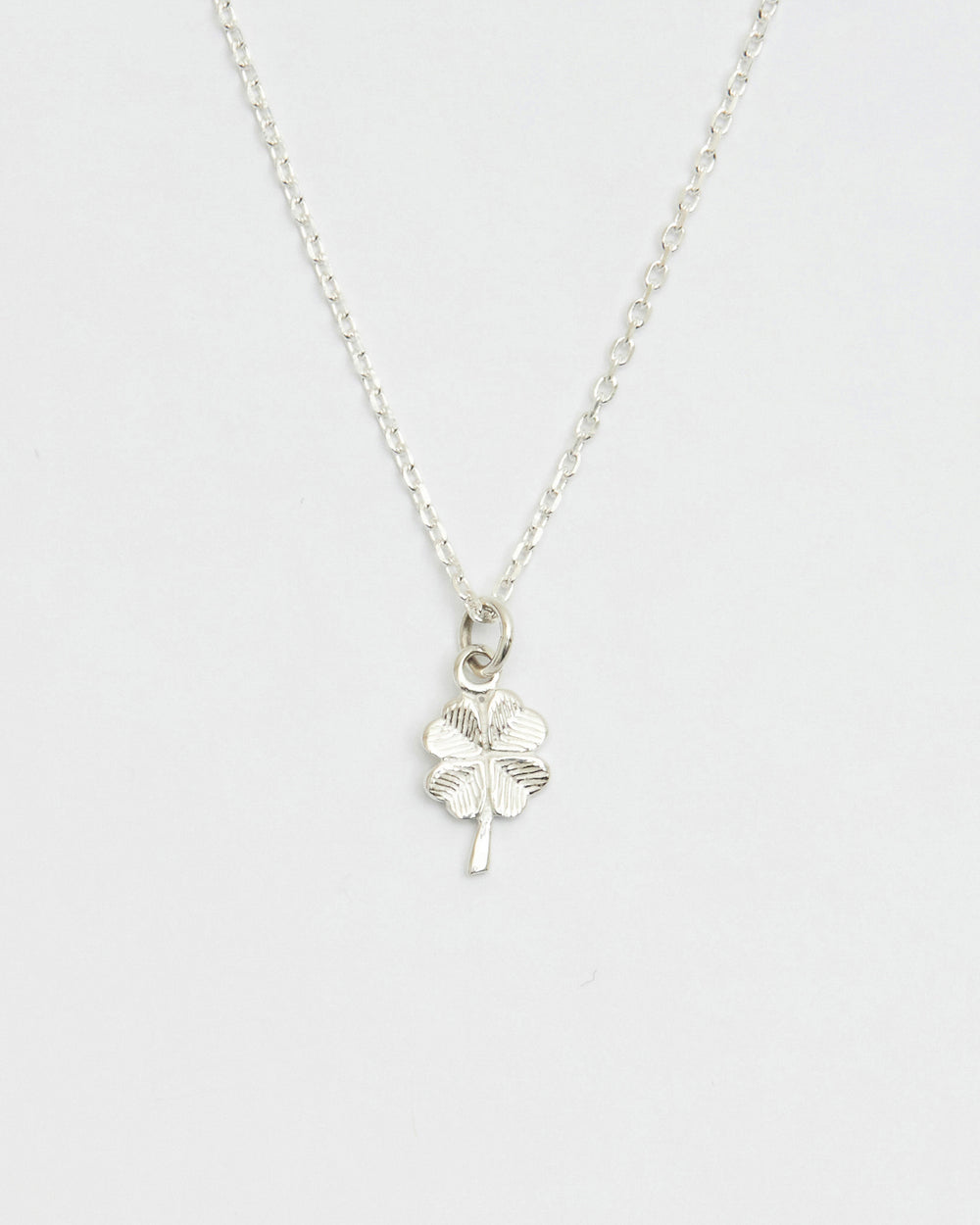 Minimal silver four leaf clover necklace displayed on white background