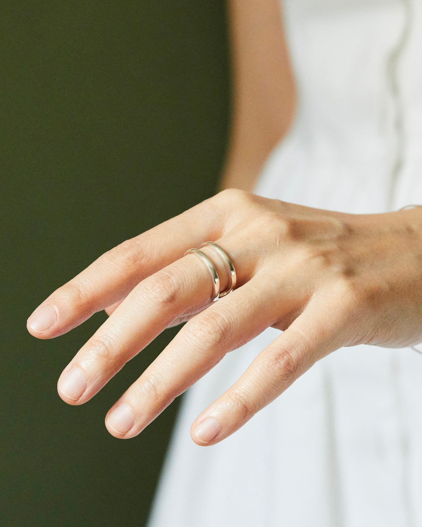 Modern sterling silver open ring worn on hand featuring smooth double-line curves and minimalist styling, shown in natural light for everyday jewelry inspiration.