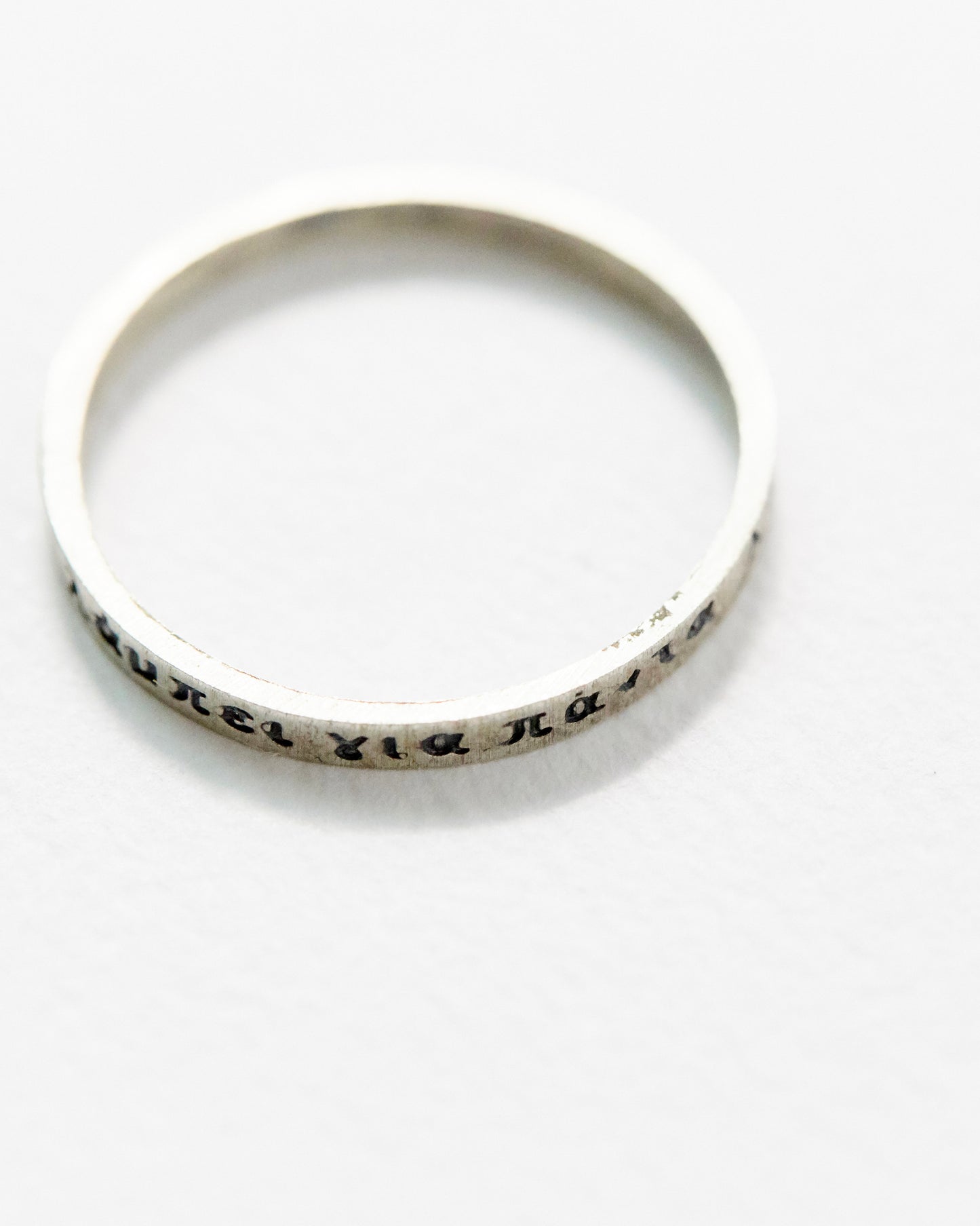 Macro close-up of engraved detail on silver ring, showing clear Greek script