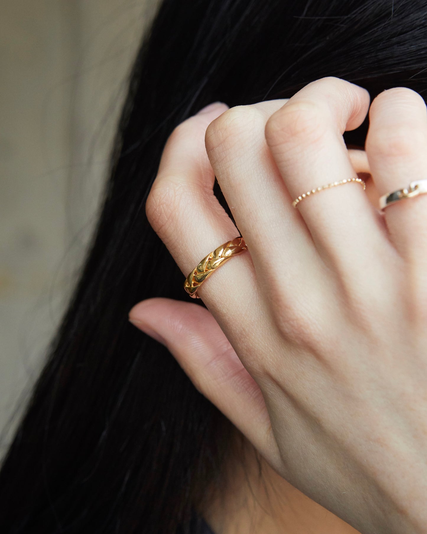 Close-up of a hand wearing gold rings with a blurred background