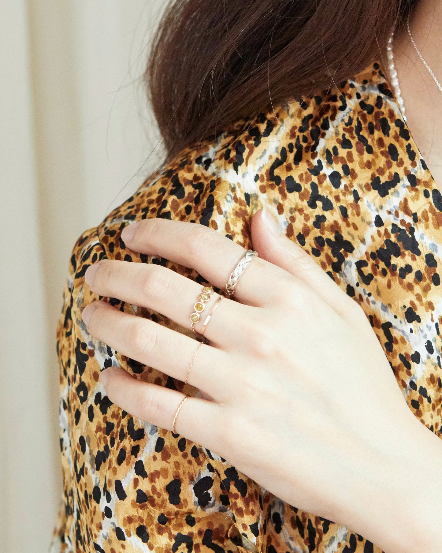 Person wearing a leopard print top with a close-up of their hand showing rings.