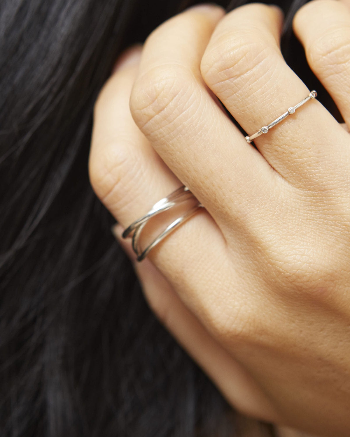 Hand in dark hair wearing a silver triple line ring and a fine dot ring – HANNA543 R506 triple air lines