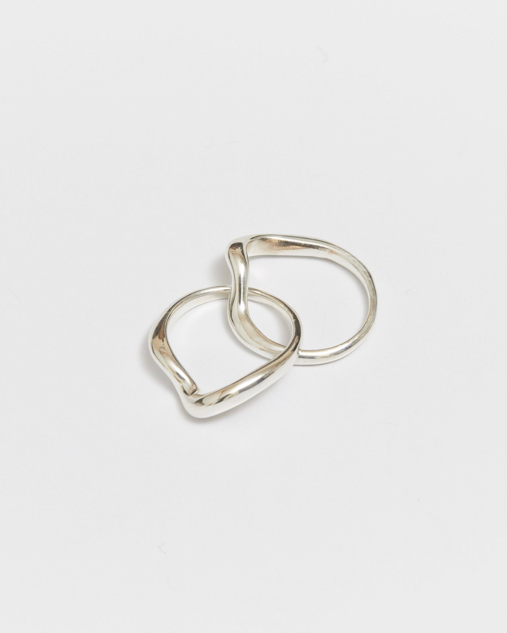 Two interlocking gold rings with softly curved bands on a white background