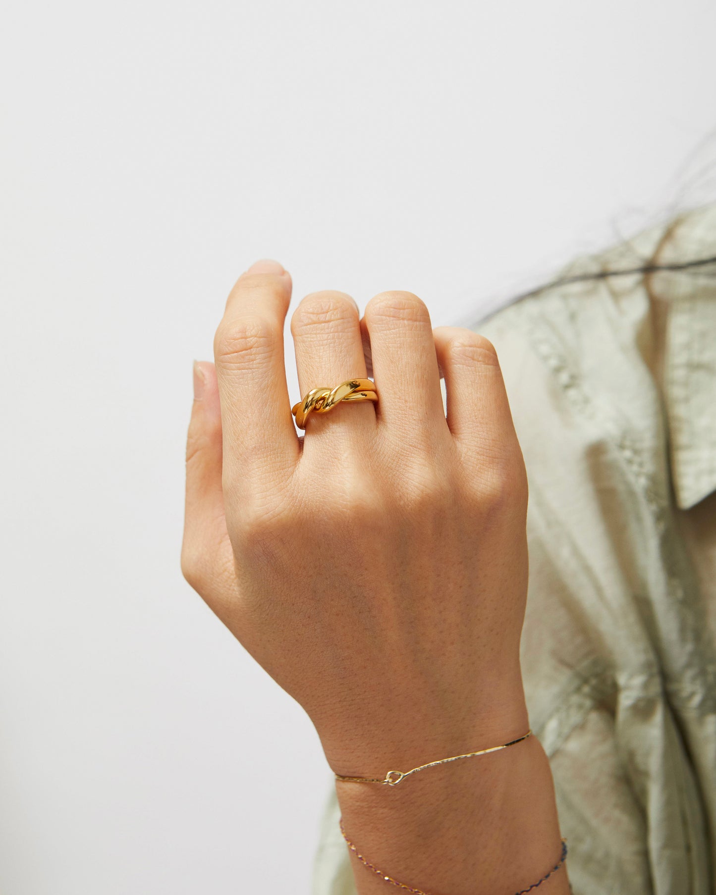 Hand wearing a gold ring on a light background