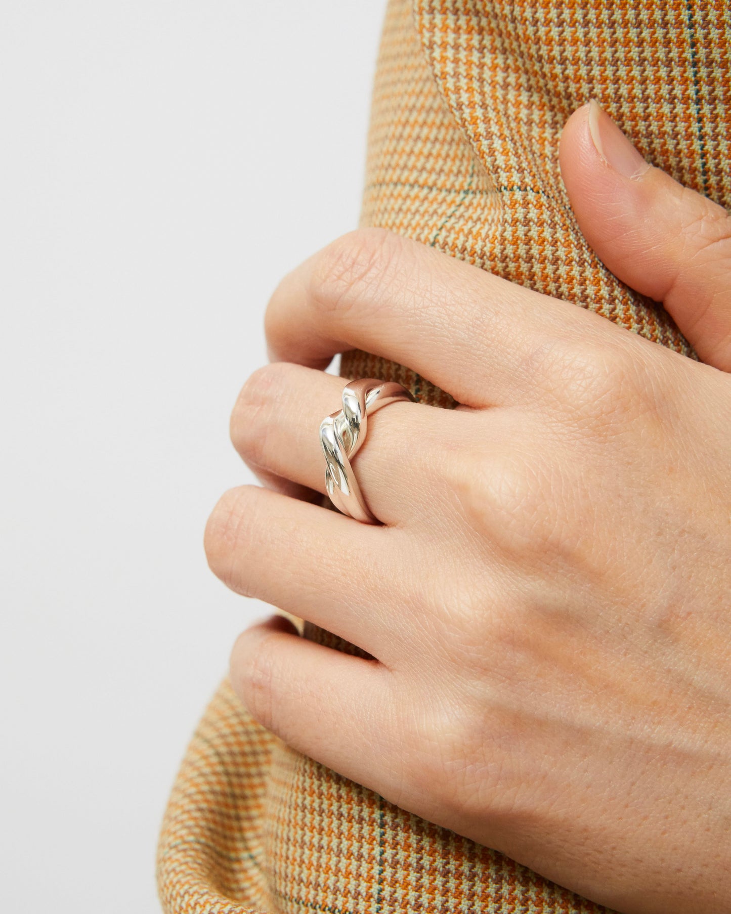 Silver ring with twist detail worn on model’s hand, styled casually