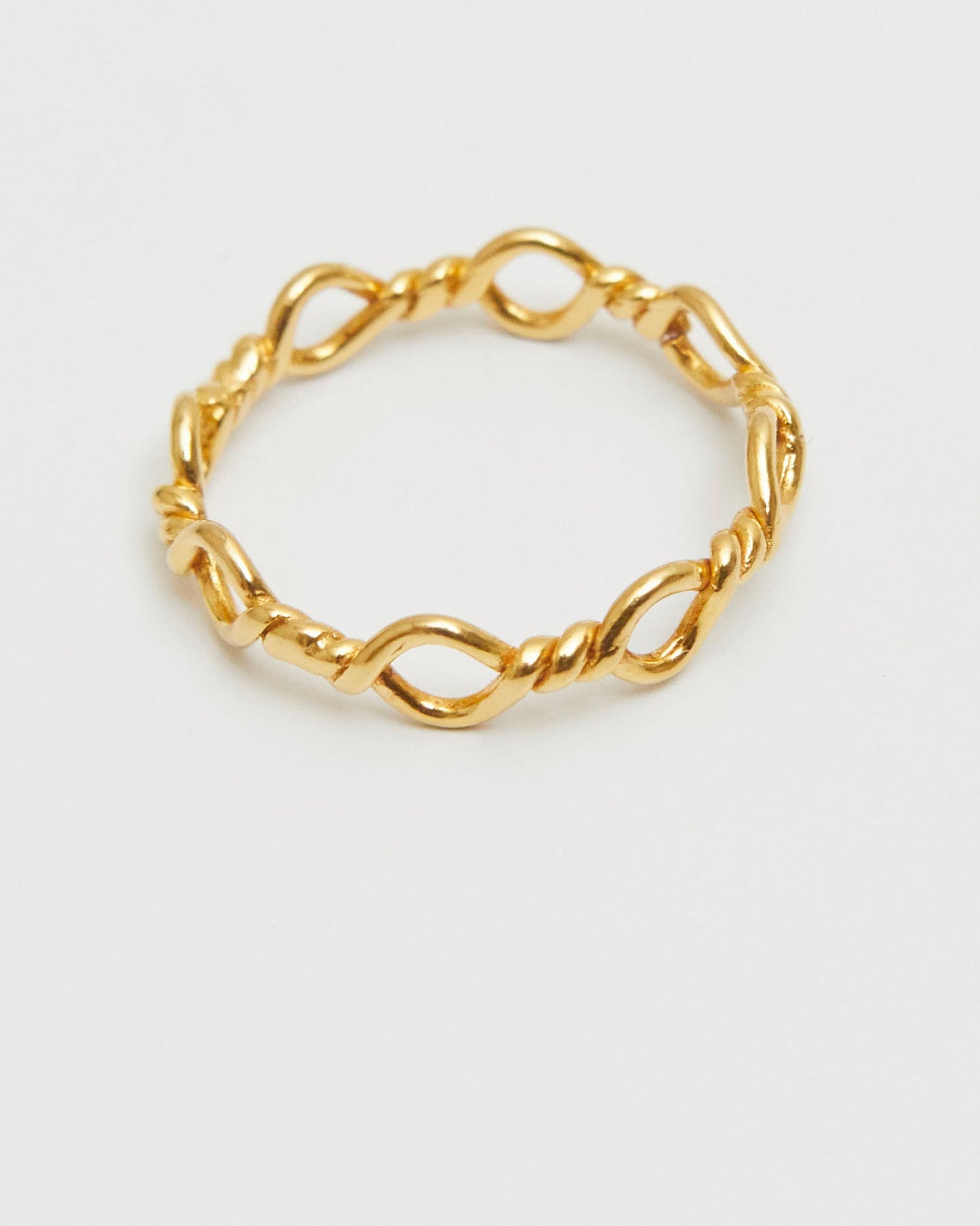 minimal gold loop ring resting in soft light, quiet and restrained composition