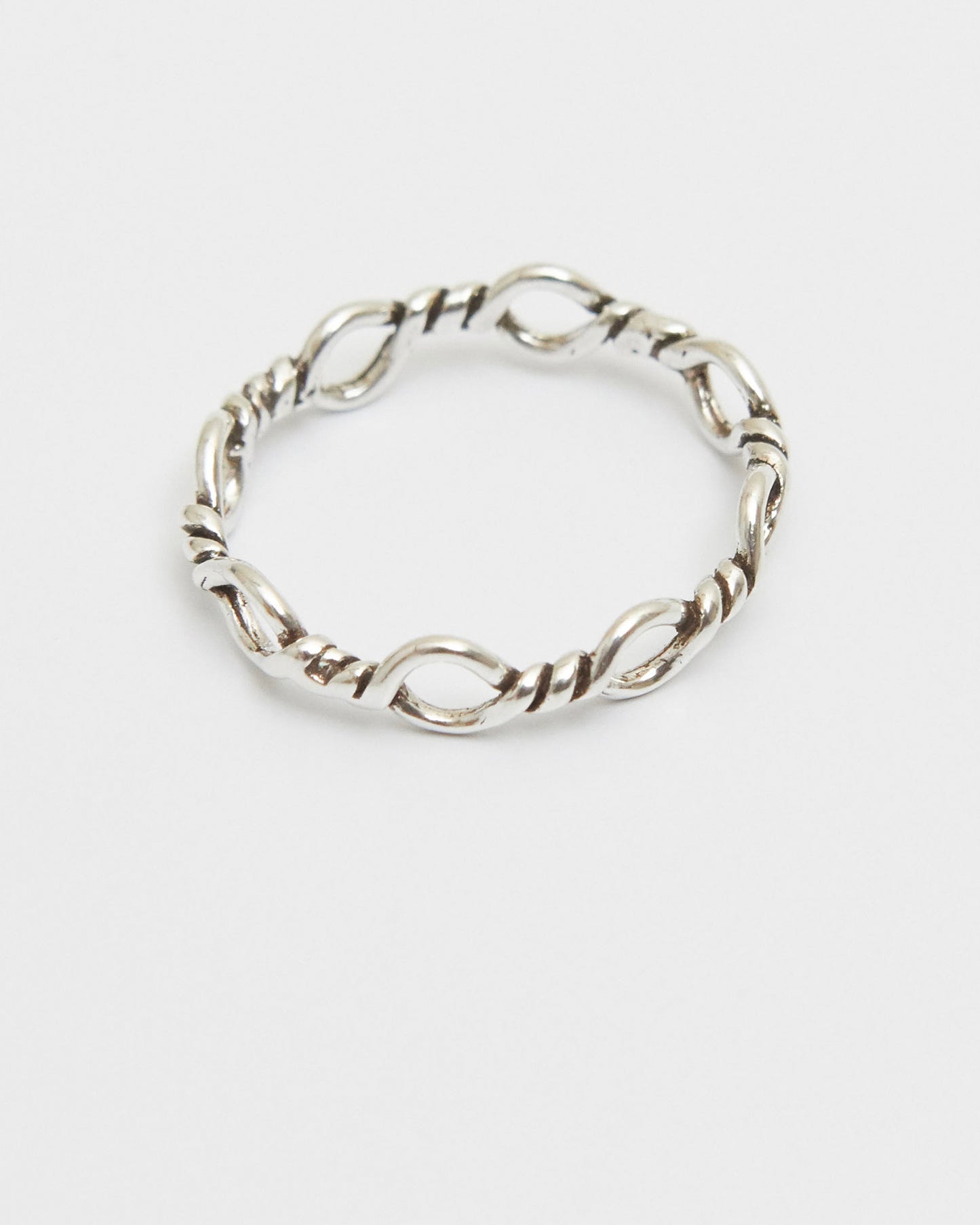 minimal silver loop ring resting in soft light, quiet and restrained composition