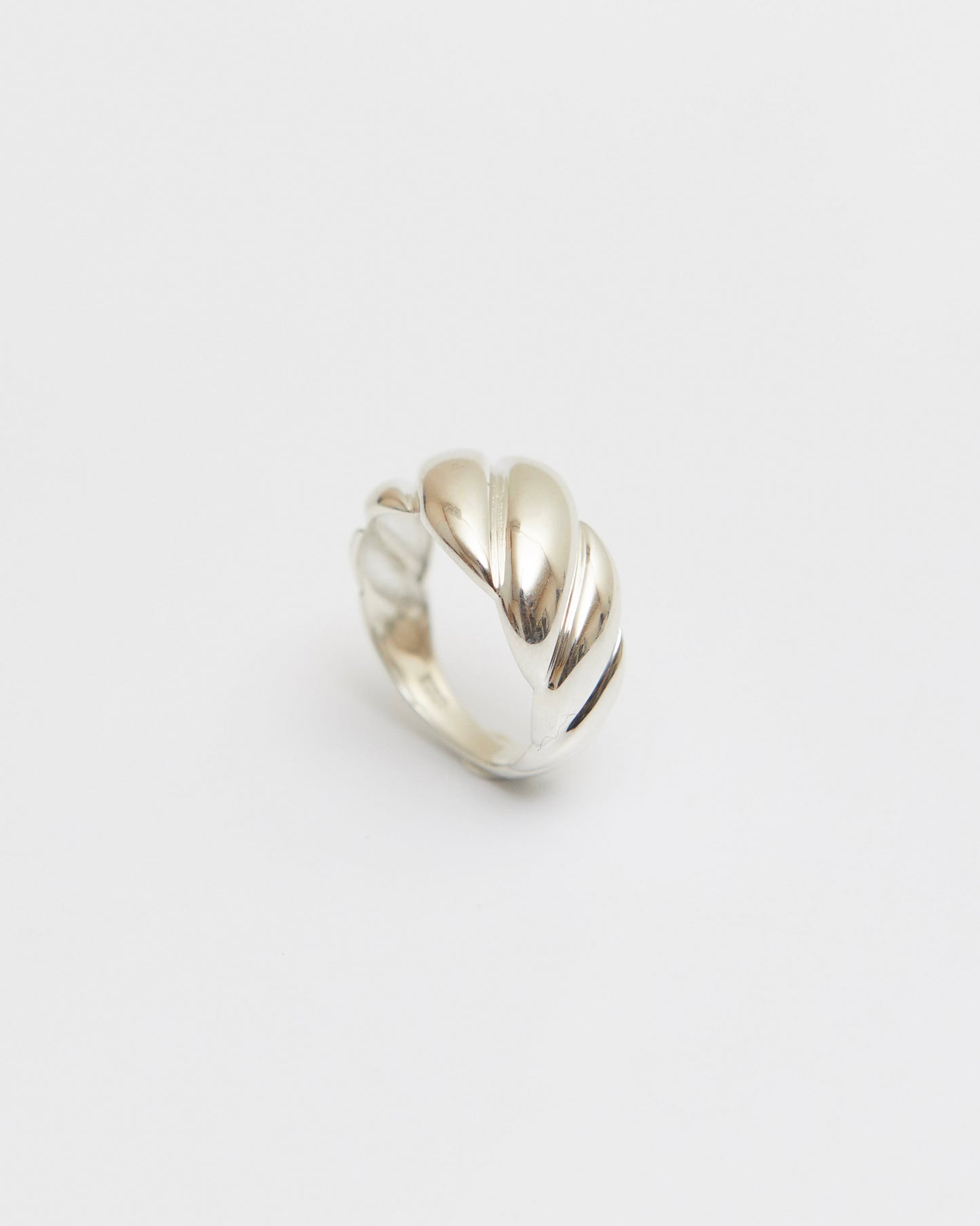 minimal twisted ring resting in soft light, sculptural and calm composition